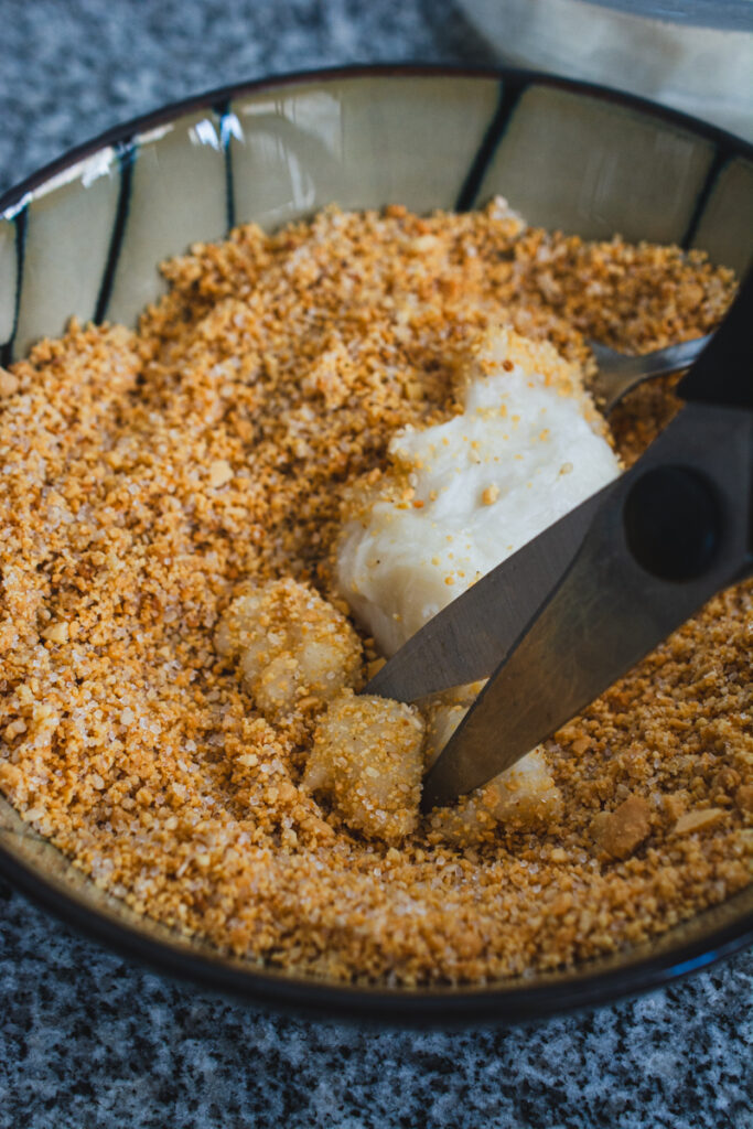 cutting muah chee dough in chopped peanut mixture