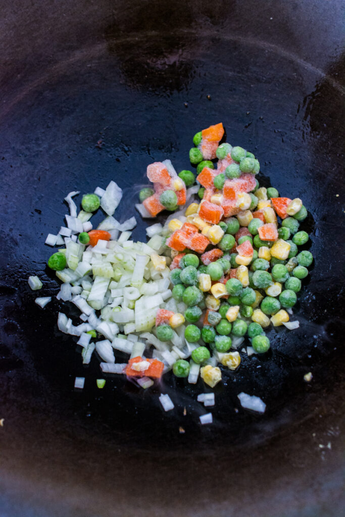 frozen veggies and diced onions in a wok