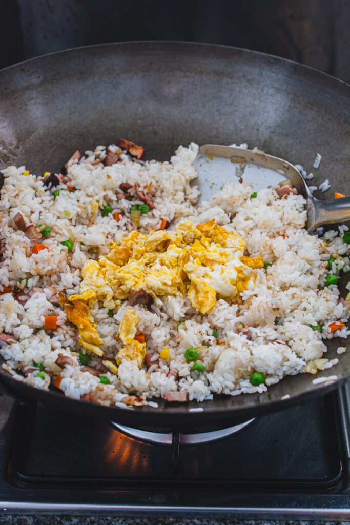 cooked  rice and vegetables with scrambled eggs in a wok