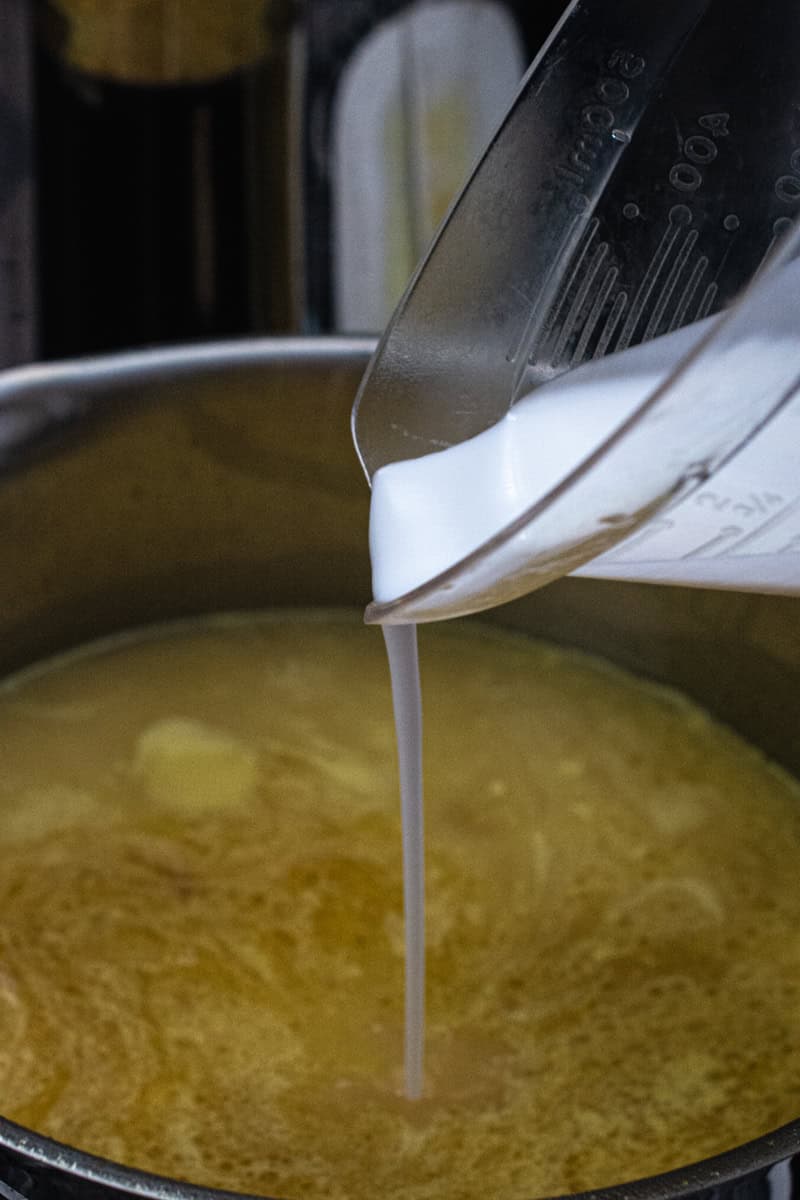 pouring coconut milk into soto ayam broth